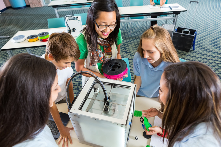 Teacher teaching students to load filament into 3D printer